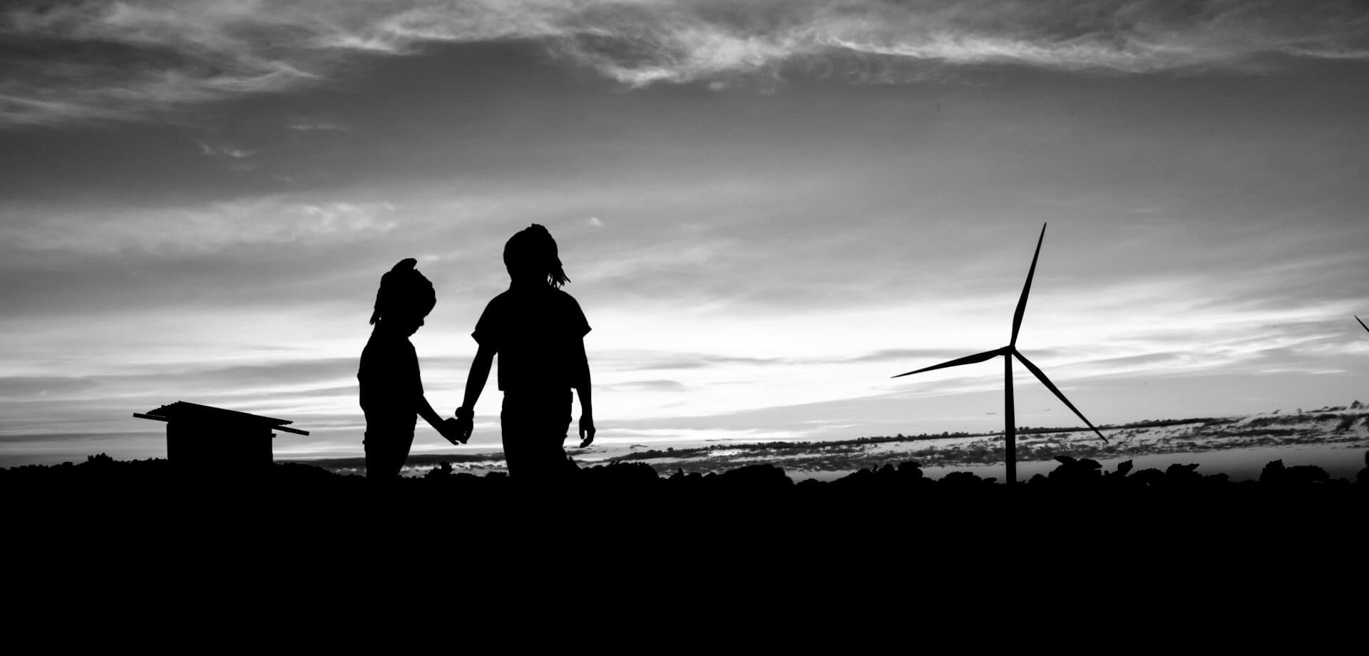 Silhouette wind turbines and cottage at sunsetloading=