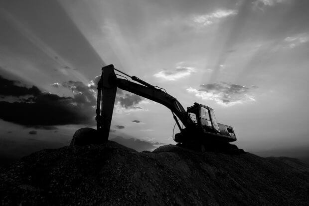 Silhouette excavator working on construction site.